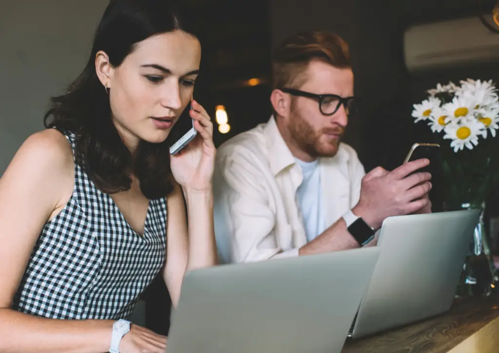 Deux personnes travaillant sur leurs ordinateurs, illustrant l’analyse des indicateurs de performance en prospection B2B.